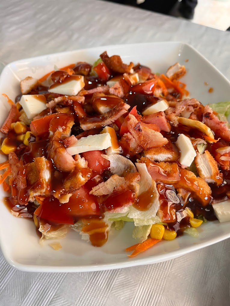 Ensalada mixta con pollo, maíz, tomate y queso bañada en salsa barbacoa
