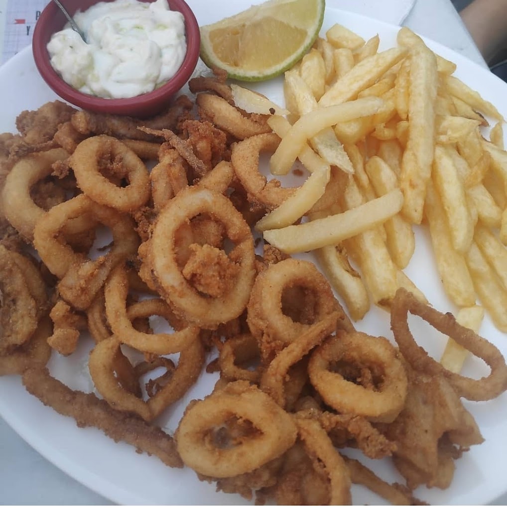 Plato de calamares fritos y patatas fritas con alioli y limón.